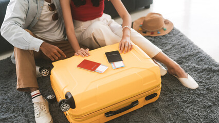 Young adult southeast asian couple hand place on luggage with passport for getting ready for...