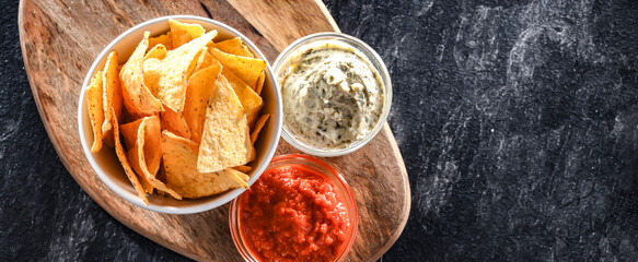 Composition with a bowl of tortilla chips and dipping sauces