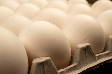 White chicken eggs in a cardboard box on the table. Close-up, selective focus