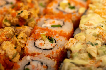A set of different types of rolls in a box. Top view of various portions of vegetarian and fish rolls.