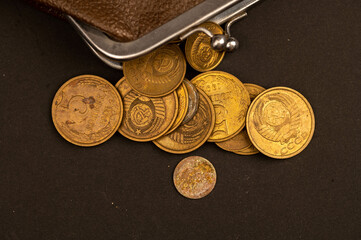 Old coins of the USSR and a vintage wallet made of brown leather on a wooden surface.