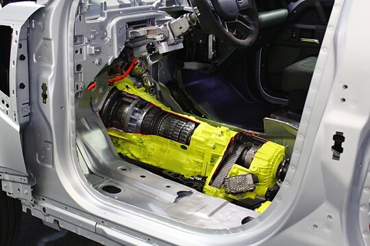 Partially opened gear-box on demonstration framework of Land Rover Defender off road four-wheel-drive SUV car - electric cables and systems are in orange color, gear-box chassis is yellow. 