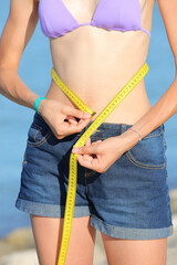 skinny girl measures the waist with tape measure