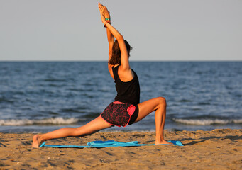 slender girl does gymnastic exercises at the beach on the gym mat