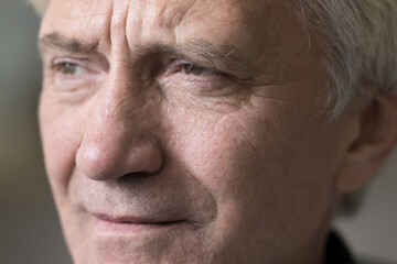 Cropped shot, wrinkled face of serious senior thoughtful male looking into distance, recollect, memories, remembers past years, is in melancholic or depressed mood. Older man close up portrait view