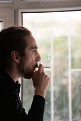 man smoking cigarette at window