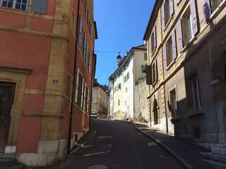 Fototapeta na wymiar Historical old colourful buildings. Cityscape of colourful red brick old houses and buildings. Old rooftops cityscape from red bricks tiles on the top. Summer day travel city view in Switzerland alley