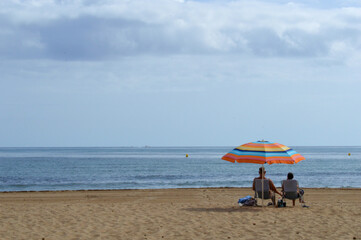 Obraz premium couple enjoying sun under umbrella on the beach
