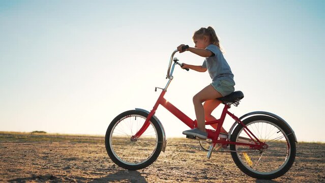 go everywhere. Child travel by bike. Happy cheerful child is playing in nature. The kid plays in park in summer. Freedom and joy on vacation. Safe transport in the field. Kid learning to ride a bike