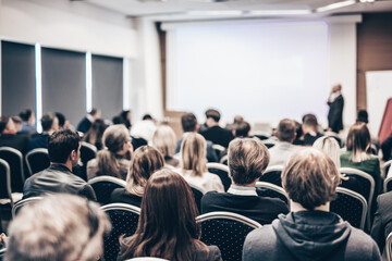 Speaker giving a talk in conference hall at business event. Rear view of unrecognizable people in...
