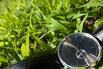 Black wrist watch in green grass as concept for time running out for reversing climate change and becoming net zero per the EU Taxonomy and Paris Agreement