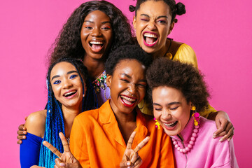 Group of Beautiful black women posing in studio on colored background with colorful fashionable...