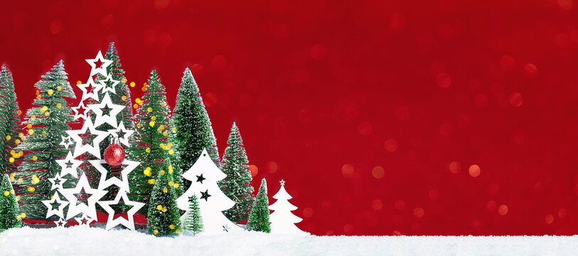 Many christmas trees with snow and wooden trees with red bauble. Merry Christmas and a Happy New Year banner with borders. Seasons greetings card. Red background