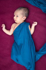 newly born baby laying on red velvet cloth with cute facial expression from different angle