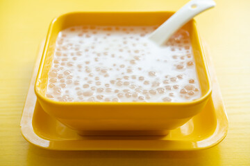 angle view bowl of Chinese syrup of sago with coconut juice on yellow background - obrazy, fototapety, plakaty