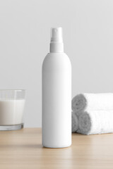 Obraz na płótnie Canvas White cosmetic spray bottle mockup with a candle and towels on the wooden table.