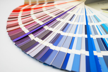 Color guide close up. Assortment of colors for design. Colors palette fan on white concrete wall background. Graphic designer chooses colors from the color palette guide.