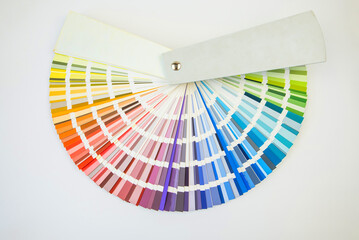 Color guide close up. Assortment of colors for design. Colors palette fan on white concrete wall...