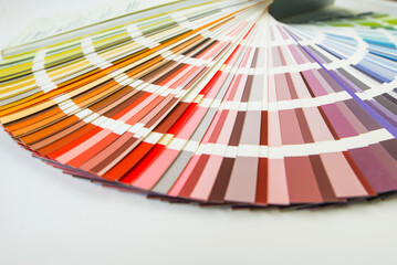 Color guide close up. Assortment of colors for design. Colors palette fan on white concrete wall background. Graphic designer chooses colors from the color palette guide.