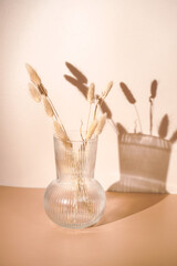 A bunch of yellow wheat spikes, Reeds foliage branches in a transparent rippled vase on orange and...