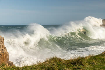Big waves breaking against the cliffs. Huge waves in the coast during a sea storm. Maritime storm.