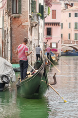 Fototapeta na wymiar Gondoliers et leur gondole sur un canal dans Venise.