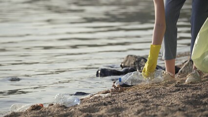 volunteer collects plastic trash in the park. recycle plastic bottle cleanup ecology concept blurred background.
