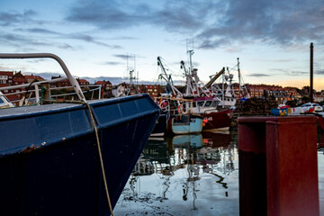 Close and selective focus on the front end of a small fishing boat moored in Whitby docks at dusk