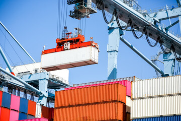 A view of a crane preparing to latch onto a shipping container.