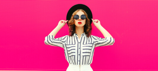 Beautiful young woman model wearing white striped shirt, black round hat, skirt on pink background