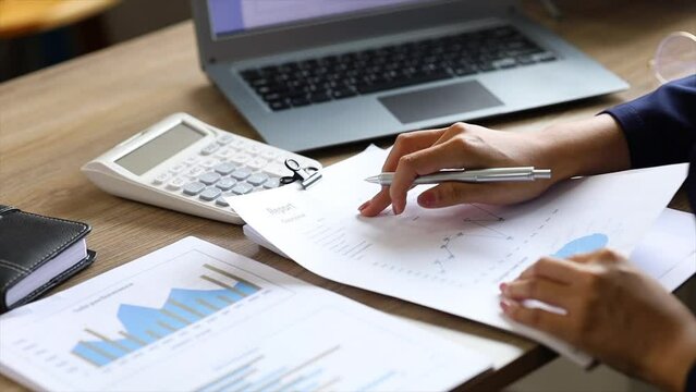 A female financier is reviewing company financial documents, monthly financial statement summary from the finance department. The concept of managing the company's finances for accuracy and growth.