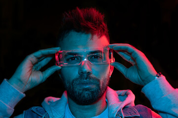 Serious man in the glasses in the neon lights close up portrait in dark background 