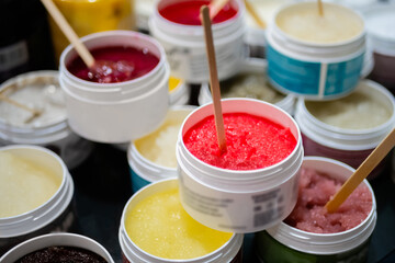 Set of jars with natural body, face scrub with wooden stick on counter of cosmetic store. Treatment, care and wellness concept