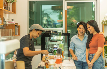 A couple of female LGBTQ is taking coffee service from a startup shop. Female couple is enjoy having refreshment at a coffee corner.  Female barista is serving drinks to customers