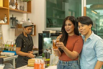 A couple of female LGBTQ is taking coffee service from a startup shop. Female couple is enjoy...