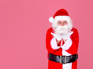 A gray-haired cheerful man in a Santa suit looks at his hands in white gloves. An idea for a Christmas advertisement. Isolate