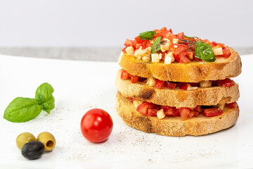 Primo piano di bruschetta cibo italiano con pomodori, basilico, olio pepe e olive caldi colori estivi