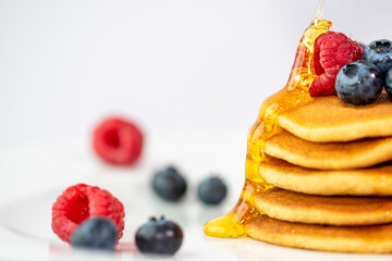 Primo piano di pancake con miele, more e mirtilli con caldi colori autunnali
