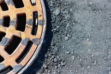 A cast-iron storm sewer hatch on the road before laying the asphalt pavement poured with bitumen. Drainage of rainwater from the road surface. Close-up.