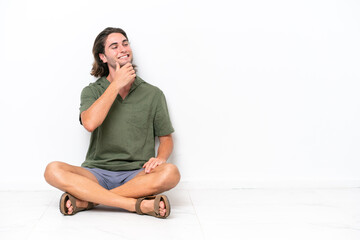 Fototapeta na wymiar Young handsome man sitting on the floor isolated on white background looking to the side