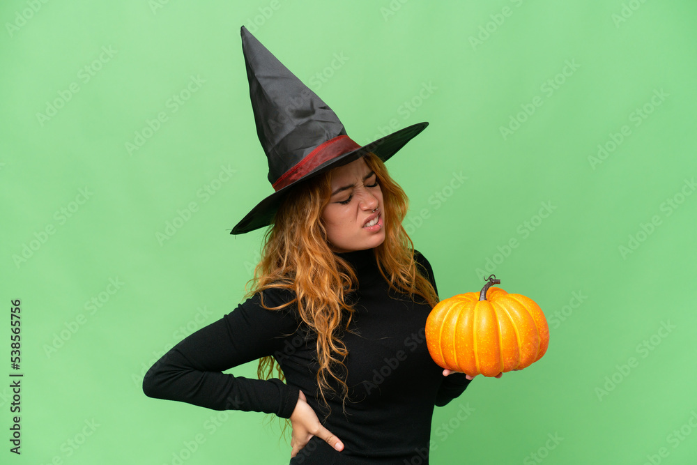 Wall mural Young caucasian woman costume as witch holding a pumpkin isolated on green screen chroma key background suffering from backache for having made an effort