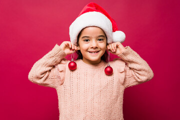 Adorable kid using christmas balls as earrings