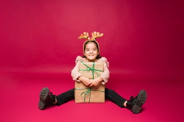 Cute young kid holding her christmas gifts and smiling