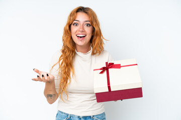 Young caucasian woman holding a gift iso0lated on white background with shocked facial expression