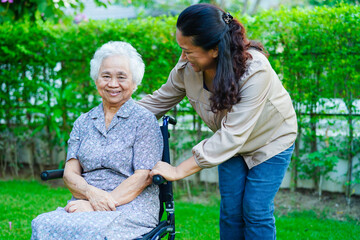 Caregiver help Asian elderly woman disability patient sitting on wheelchair in park, medical concept.