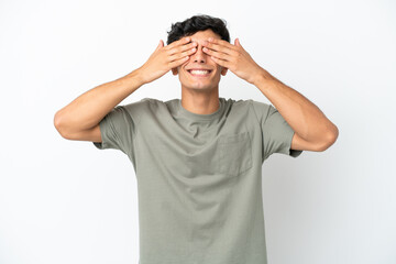 Young Argentinian man isolated on white background covering eyes by hands and smiling