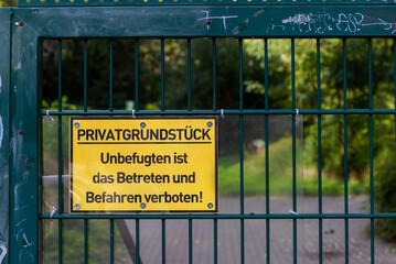 Yellow sign on a fence with the inscription: Private property, unauthorized persons are not allowed to enter or drive on! - 538569902