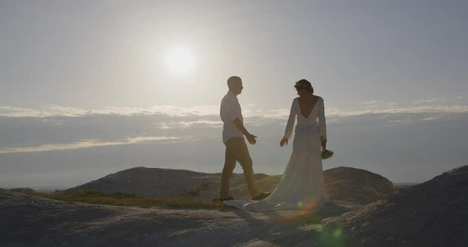 A couple in love stands high on a mountain at sunrise