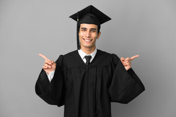 Young Argentinian university graduate isolated on grey background pointing finger to the laterals and happy
