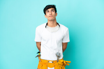 Young electrician Argentinian man isolated on blue background and looking up